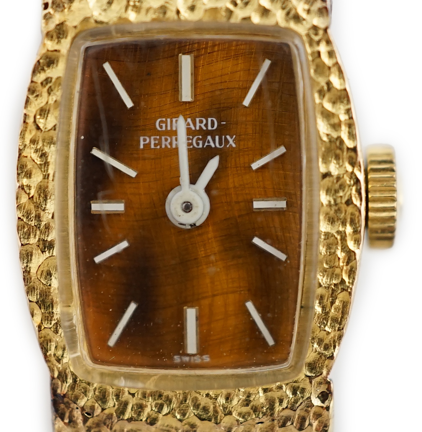 A lady's Girard Perregaux 18K cased wrist watch, with tiger's eye quartz dial, white hands and markers, on an integral yellow metal textured close-link flexible bracelet with clasp, which is stamped 18k but does not test